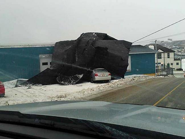 Part of a hardware store's roof is shown against the side of a building in this photo provide by Terry Osmond after high winds in Port-aux-Basque, Newfoundland on Monday Dec. 25, 2017. 