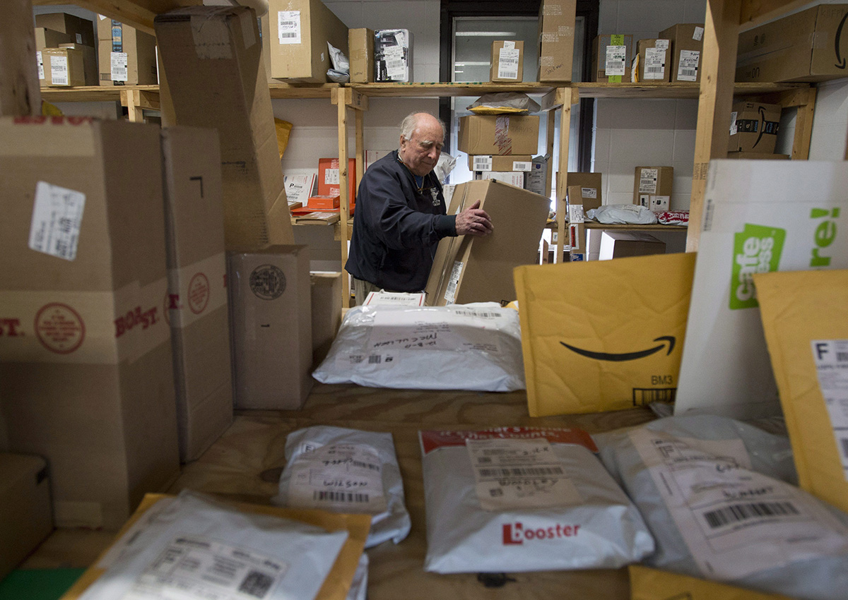 Crow Smith puts a package away in a warehouse among shipping packages waiting to be picked up Monday December 18, 2017 in Ogdensburg, N.Y. 