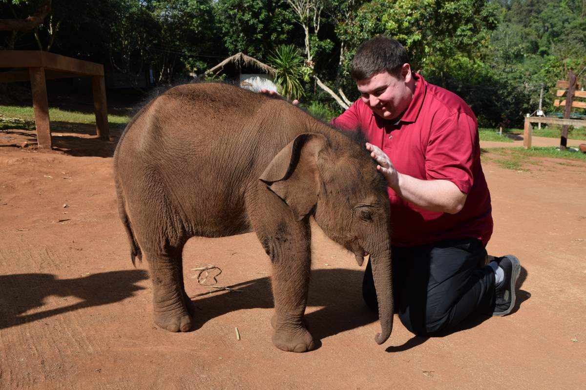 Global News radio host and columnist Andrew Lawton interacts with Gao, a 20-day old Thai elephant at Thailand's Patara Elephant Farm in Chiang Mai.