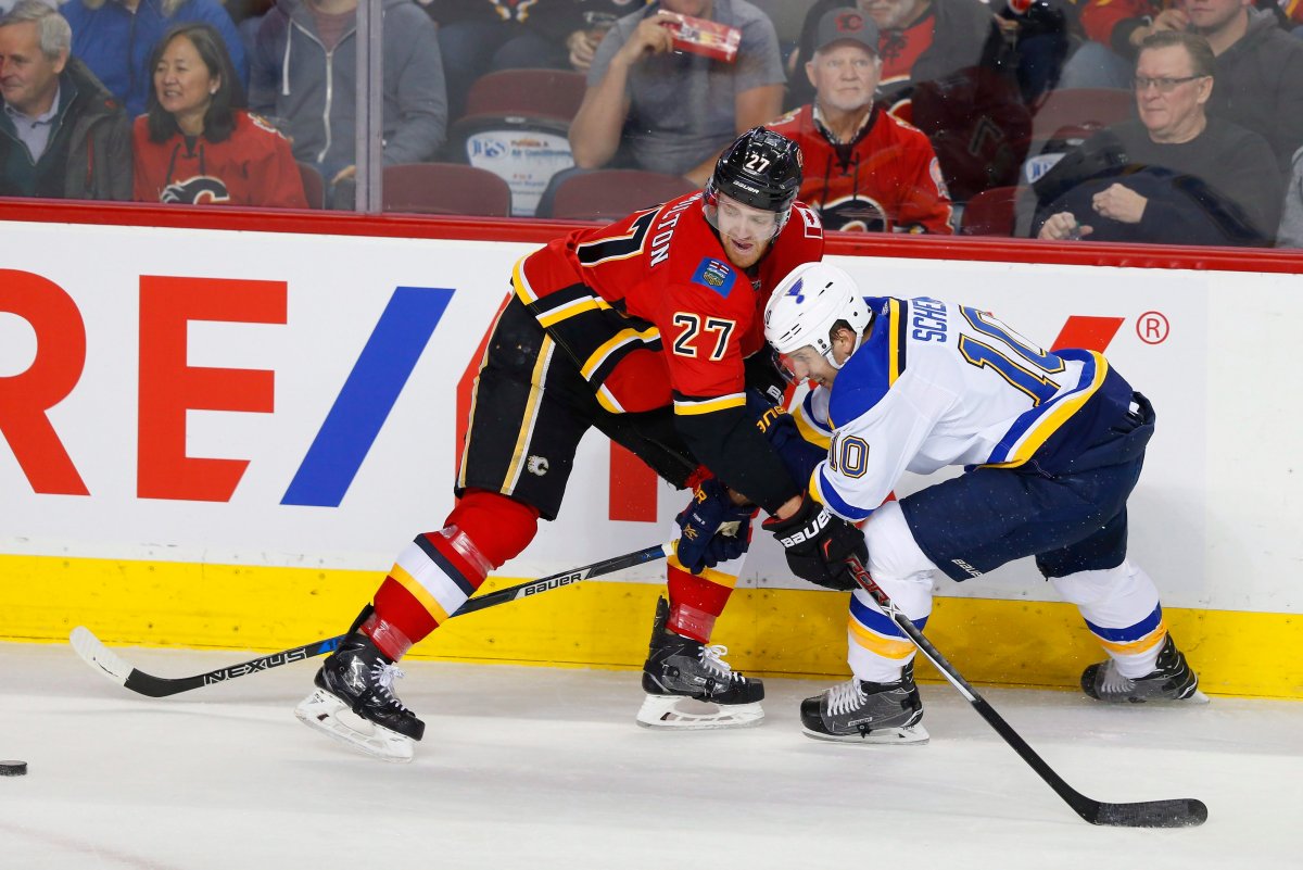 Calgary Flames Dougie Hamilton, left, battles for the puck with St. Louis Blues' Brayden Schenn during the first period of their NHL hockey game in Calgary, Wednesday, Dec. 20, 2017.