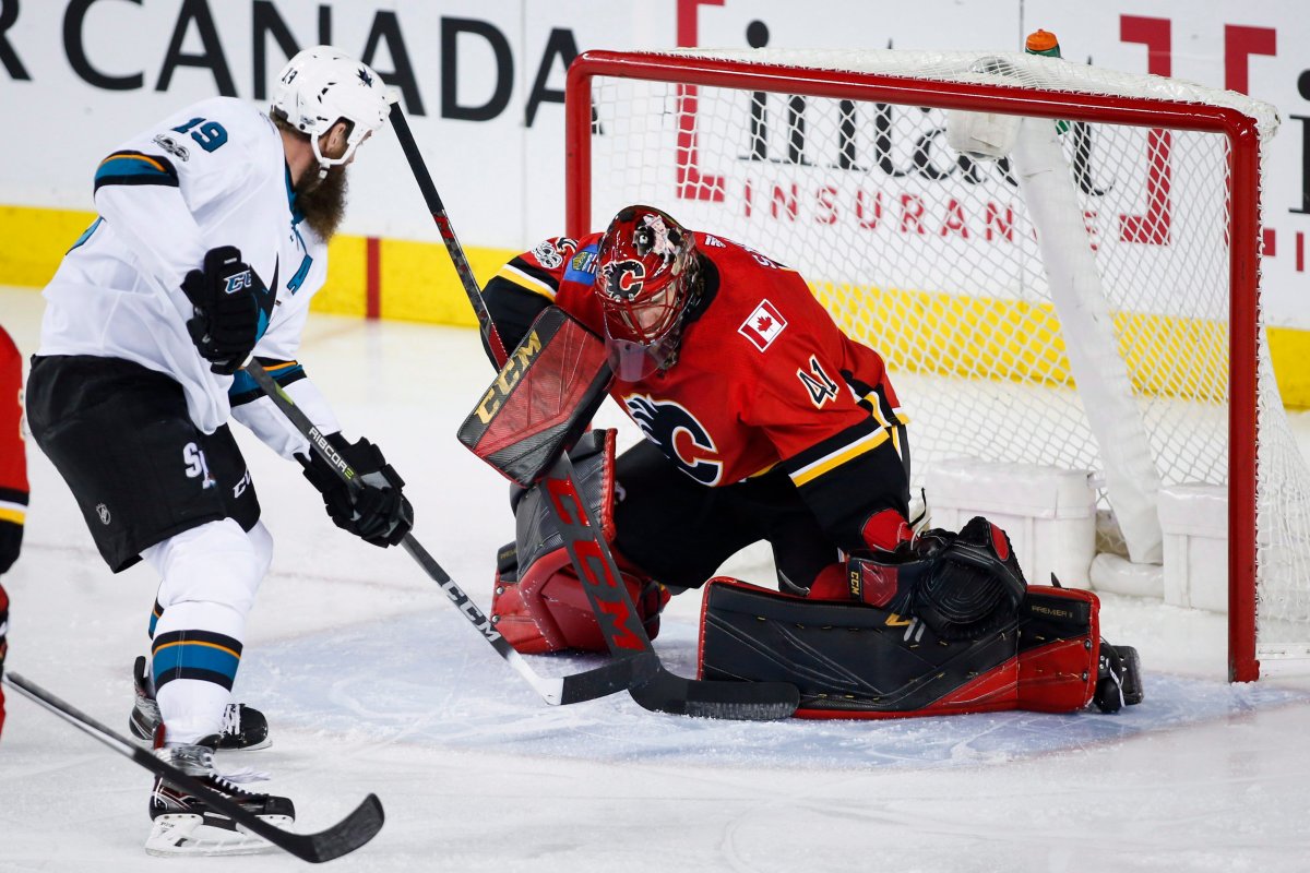 San Jose Sharks' Joe Thornton, left, has his shot blocked by Calgary Flames goalie Mike Smith during first period NHL hockey action in Calgary, Thursday, Dec. 14, 2017.THE CANADIAN PRESS/Jeff McIntosh.
