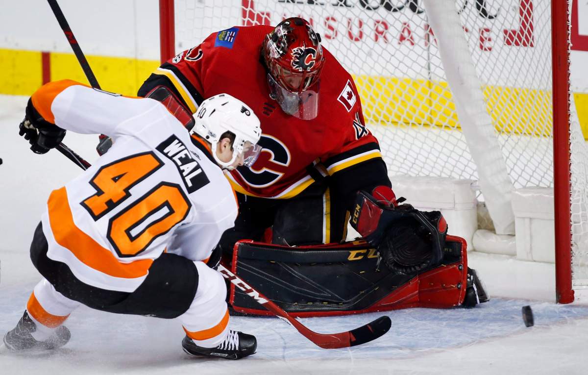 Philadelphia Flyers' Jordan Weal, left, has his shot stopped by Calgary Flames goalie Mike Smith during first period NHL hockey action in Calgary, Monday, Dec. 4, 2017. THE CANADIAN PRESS/Jeff McIntosh.