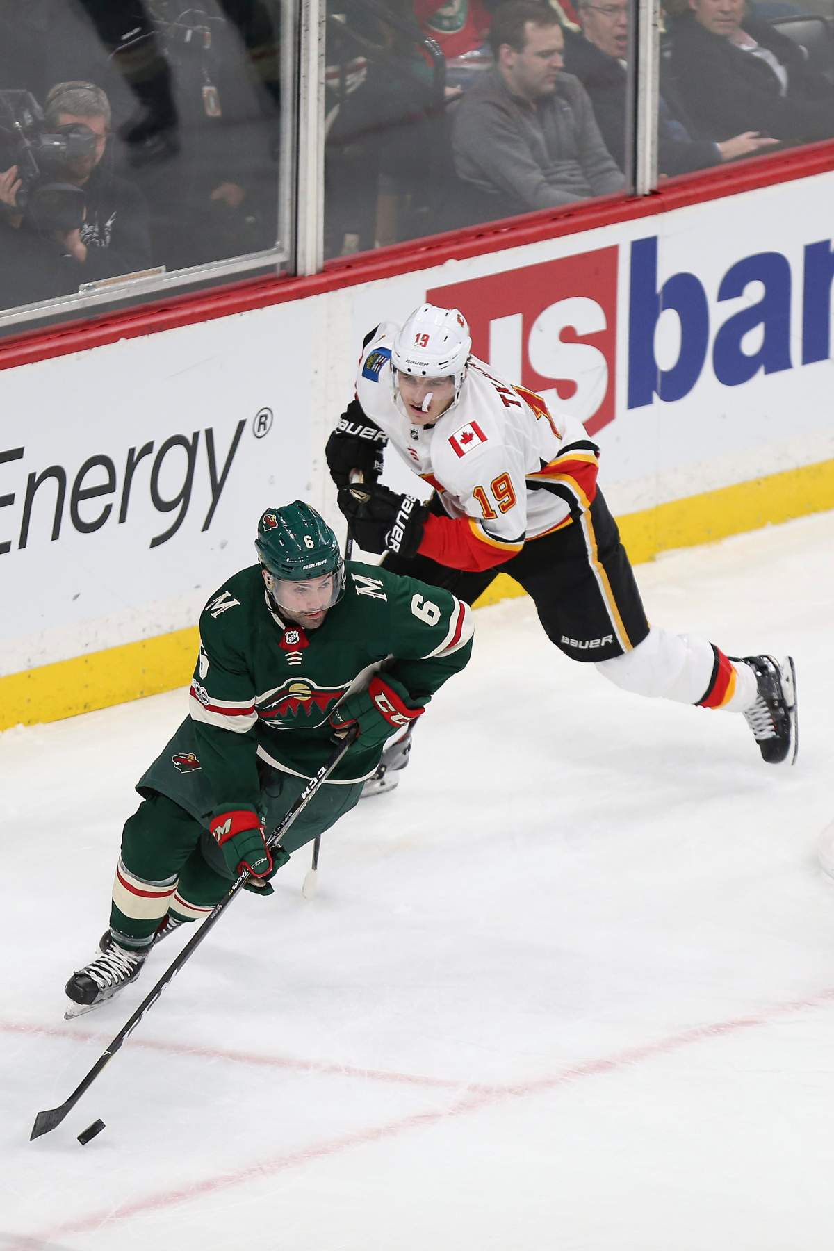 Minnesota Wild's Ryan Murphy (6) controls the puck in front of Calgary Flames' Matthew Tkachuk (19) in the third period of an NHL hockey game Dec. 12, 2017, in St. Paul, Minn. 