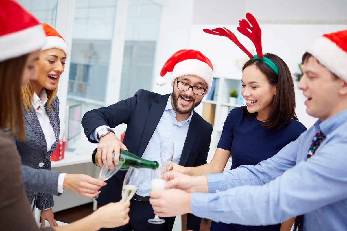 FILE -- Happy office workers in Santa caps pour champagne during a celebration in an office.