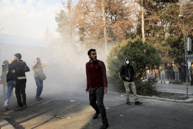 University students attend a protest outside Tehran University while a smoke grenade is thrown by anti-riot Iranian police in Tehran, Iran, Dec. 30, 2017.