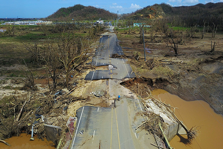 A man rides his bicycle through a damaged road in Toa Alta, west of San Juan, Puerto Rico, on September 24, 2017 following the passage of Hurricane Maria. 