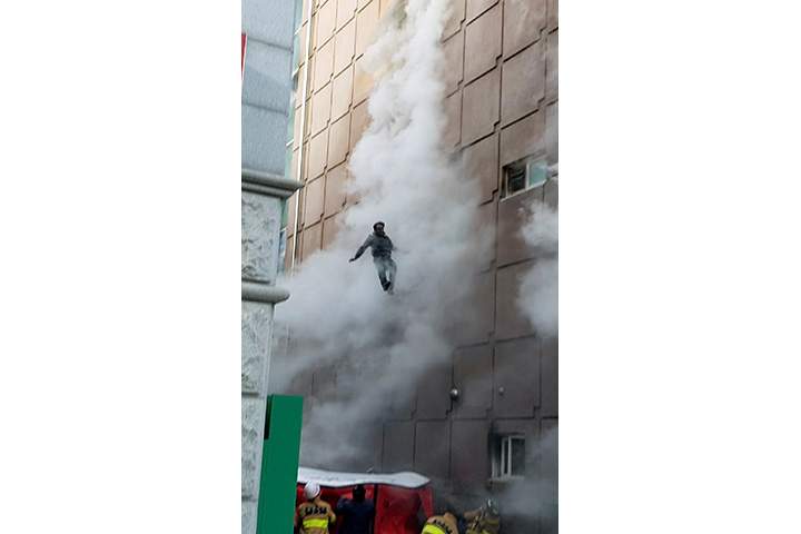 A man jumps down onto an air mattress to flee from a burning building in Jecheon, South Korea on December 21, 2017.