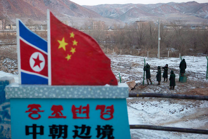 In this Dec. 8, 2012, file photo, Chinese paramilitary policemen build a fence near a concrete marker depicting the North Korean and Chinese national flags with the words "China North Korea Border" at a crossing in the Chinese border town of Tumen in eastern China's Jilin province.