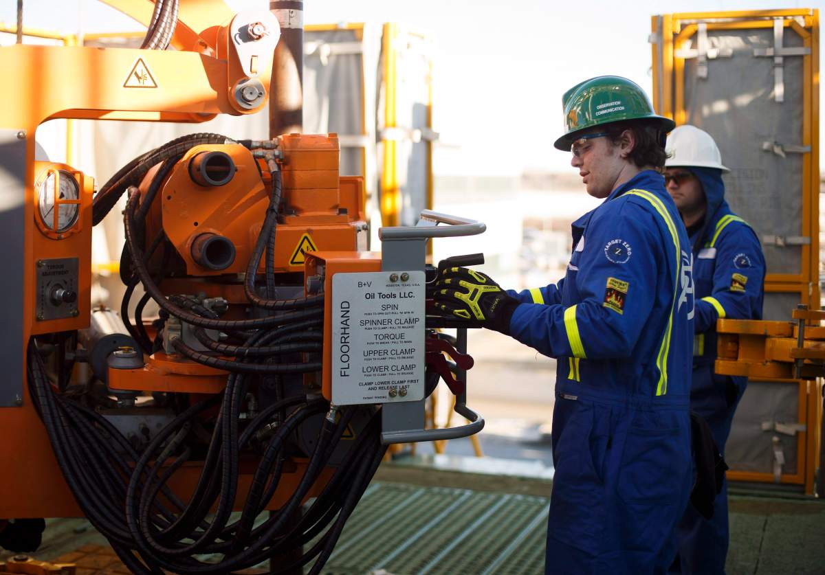 A trainee learns from an instructor on how to lay down drill pipe on a rig floor at Precision Drilling in Nisku, Alta., on Friday, January 20, 2016.