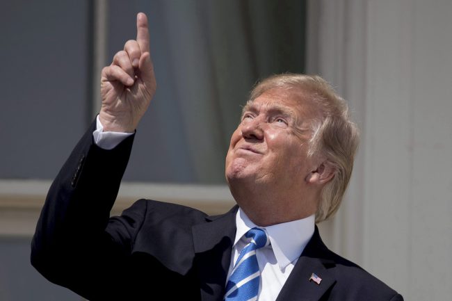 President Donald Trump points to the sun as he arrives to view the solar eclipse, Aug. 21, 2017, at the White House in Washington.