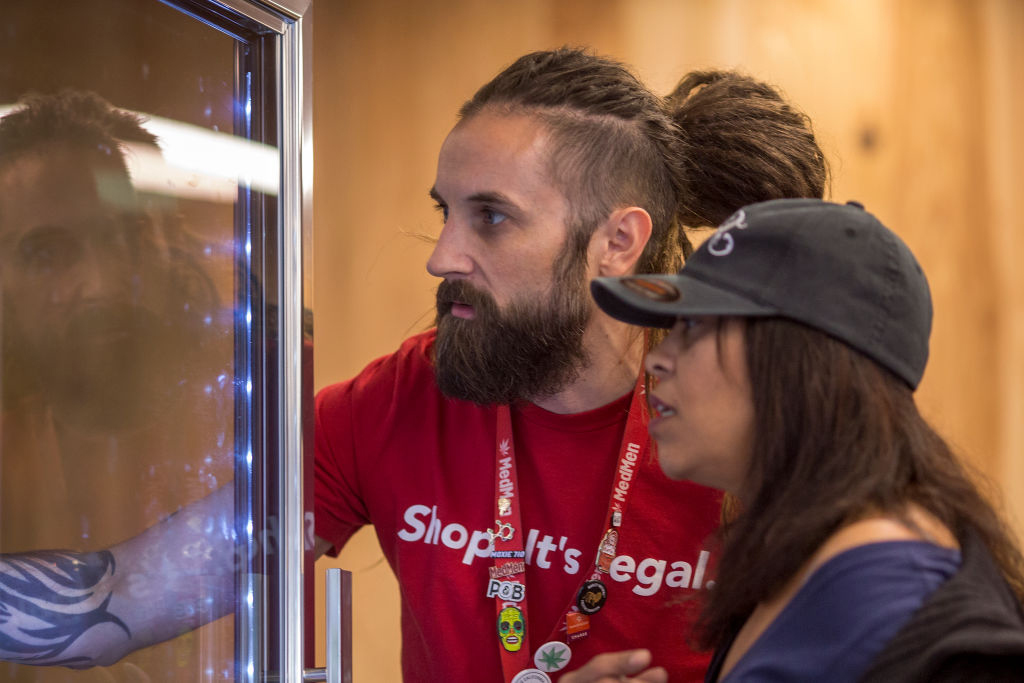 An employee of a newly legal cannabis store in California shows products to a customer on January 2, 2018. Despite what his T-shirt says, however, marijuana is still federally illegal in the U.S. 