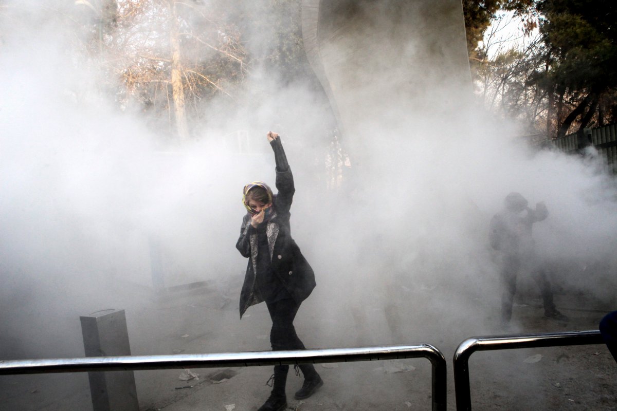 In this photo taken by an individual not employed by the Associated Press and obtained by the AP outside Iran, a university student attends a protest inside Tehran University while a smoke grenade is thrown by anti-riot Iranian police, in Tehran, Iran, Saturday, Dec. 30, 2017. A wave of spontaneous protests over Iran's weak economy swept into Tehran on Saturday, with college students and others chanting against the government just hours after hard-liners held their own rally in support of the Islamic Republic's clerical establishment. (AP Photo).