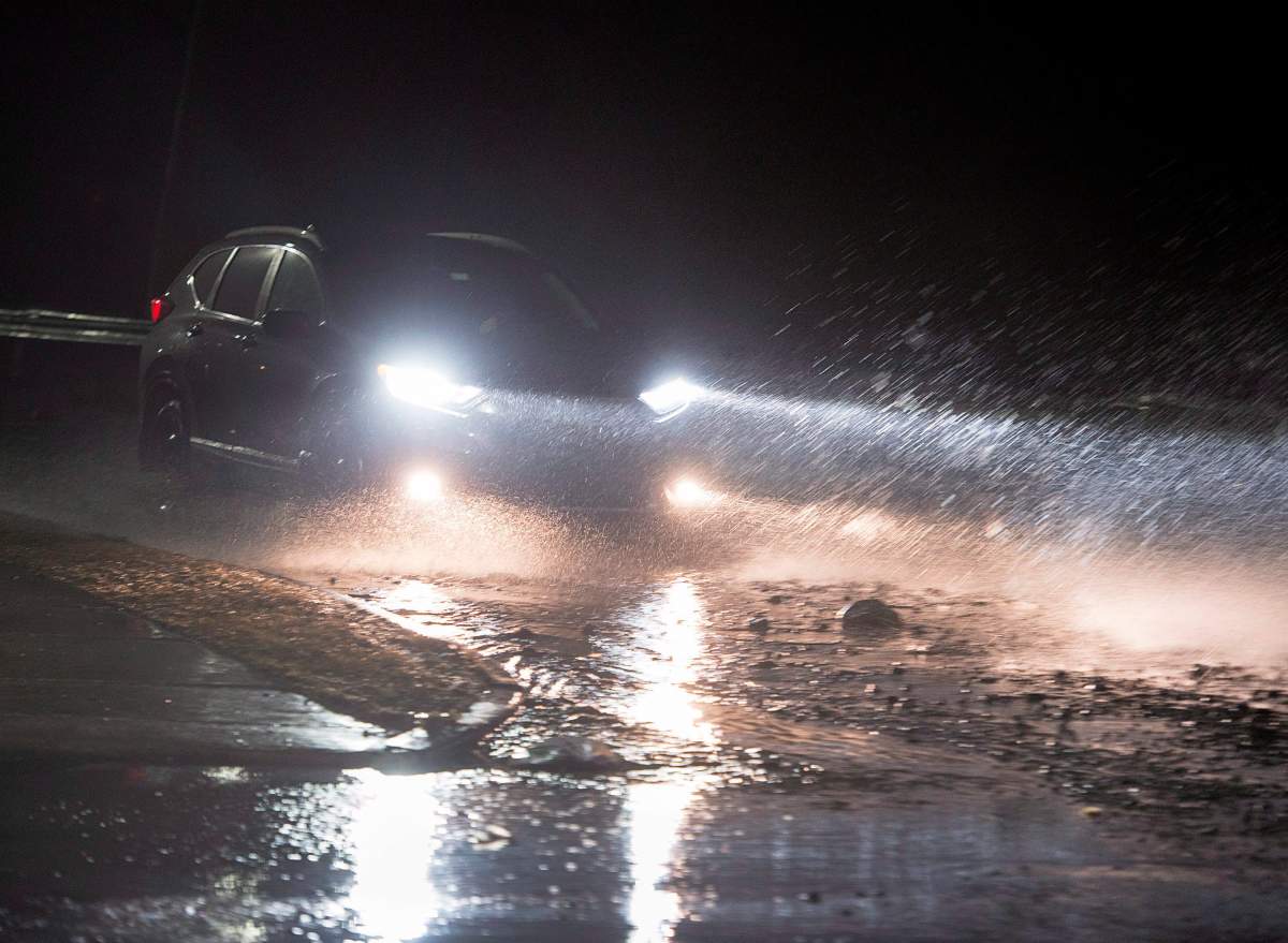 A car makes its way along Shore Road, strewn with rocks and debris tossed up by waves, in Eastern Passage, N.S. on Thursday, Jan. 4, 2018.