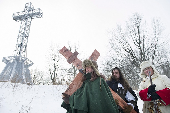 A man dressed as Paul de Chomedey de Maisonneuve, left, carries a crucifix to commemorate the 375th anniversary of the raising of the cross on Mount Royal in Montreal, Saturday, January 6, 2018.