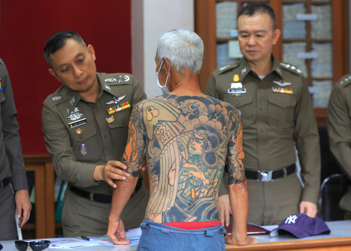 Japanese gang member Shigeharu Shirai displays his tattoos at a police station during a press conference in Lopburi, central Thailand.