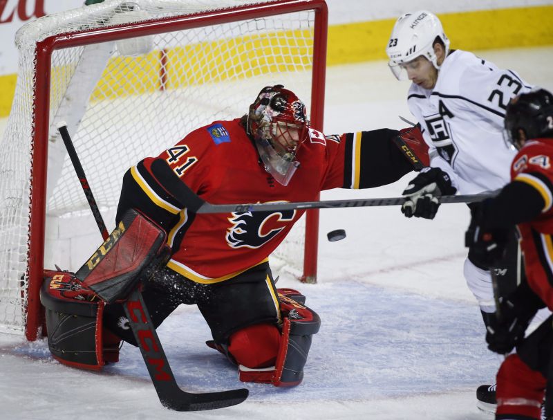 Los Angeles Kings right wing Dustin Brown (23) tries to swat the puck past Calgary Flames goaltender Mike Smith (41) during second period NHL hockey action in Calgary, Wednesday, Jan. 24, 2018.