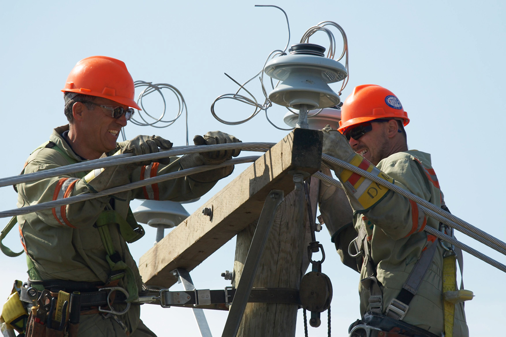 Utility line construction company linemen install new power and telephone poles in Laval, Que.