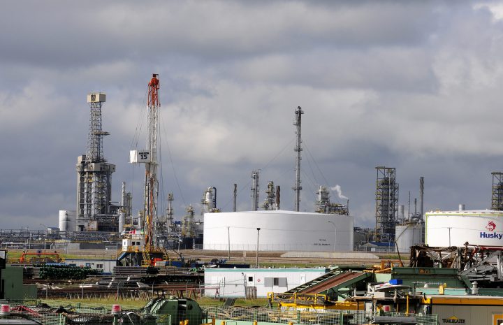An energy drilling rig belonging to Akita Drilling in front of the Husky Energy upgrader facility in Lloydminster, Sask.
