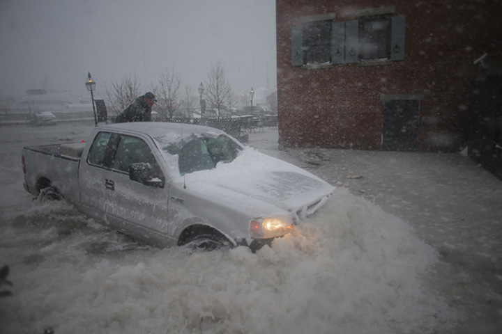 A truck drives through a flooded parking lot in Boston at high tide during on Jan. 4, 2018.