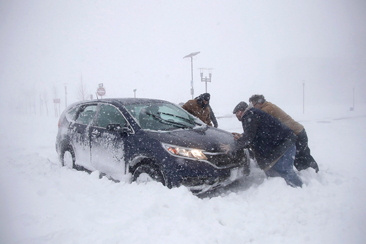 A group of men help a motorist after his vehicle was stuck in the snow on Jan. 4, 2018, in Asbury Park, N.J.