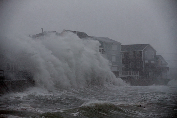 Waves crash against homes during blizzard conditions in Scituate, Mass., on Jan. 04, 2018.