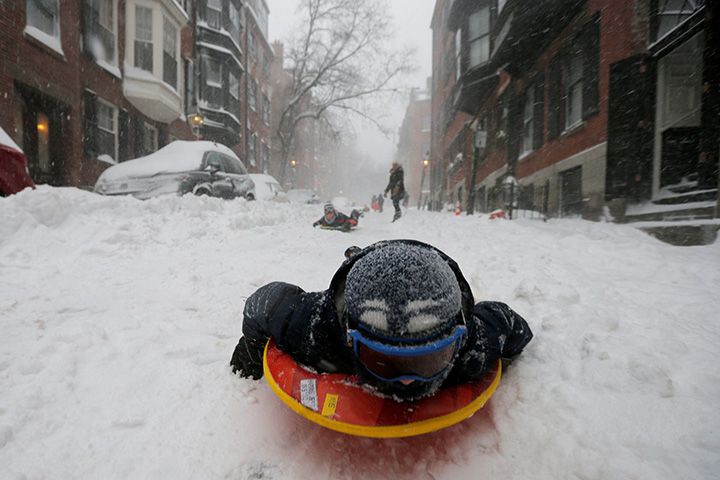 A boy sleds down a Beacon Hill street during in Boston, Massachusetts, Jan. 4, 2018.