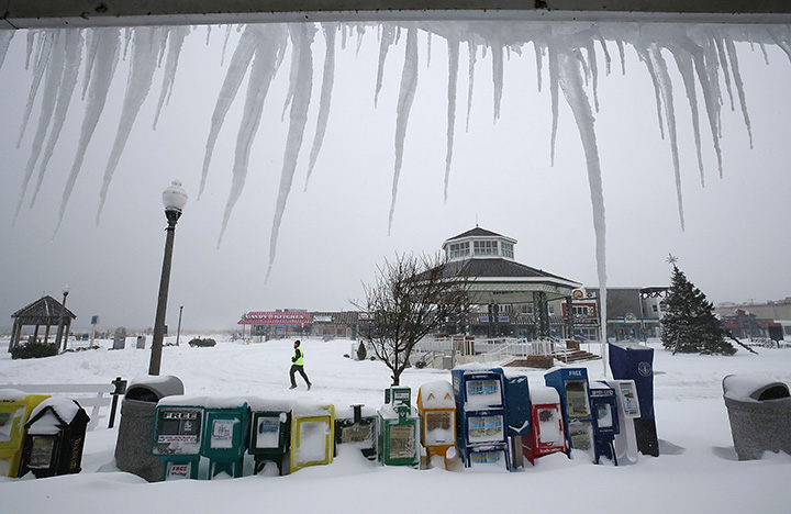 Icicles hang from a storefront as a jogger runs past in the snow on January 4, 2018 in Rehoboth Beach, Delaware.