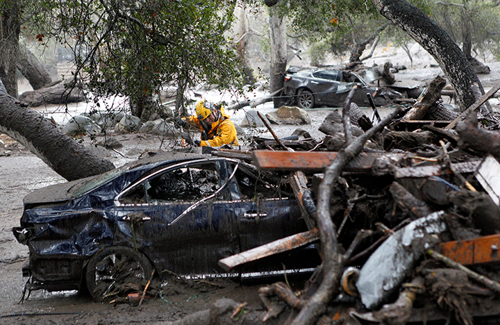 A member of a search and rescue team looks for survivors in a car in Montecito, Calif., Tuesday, Jan. 9, 2018.