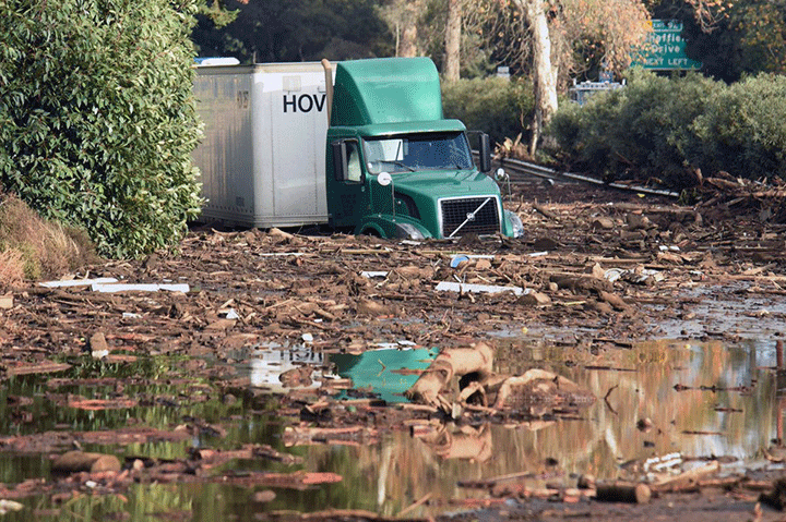 In this photo provided by the Santa Barbara County Fire Department, shows a semi-tractor trailer stuck in mud on U.S. Highway 101, in Montecito, Calif. on Tuesday, Jan. 9, 2018.