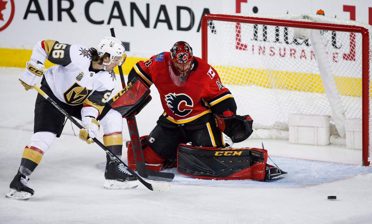 Vegas Golden Knights' Erik Haula, left, of Finland, has his shot deflected by Calgary Flames goalie Mike Smith during first period NHL hockey action in Calgary, Tuesday, Jan. 30, 2018.THE CANADIAN PRESS/Jeff McIntosh.