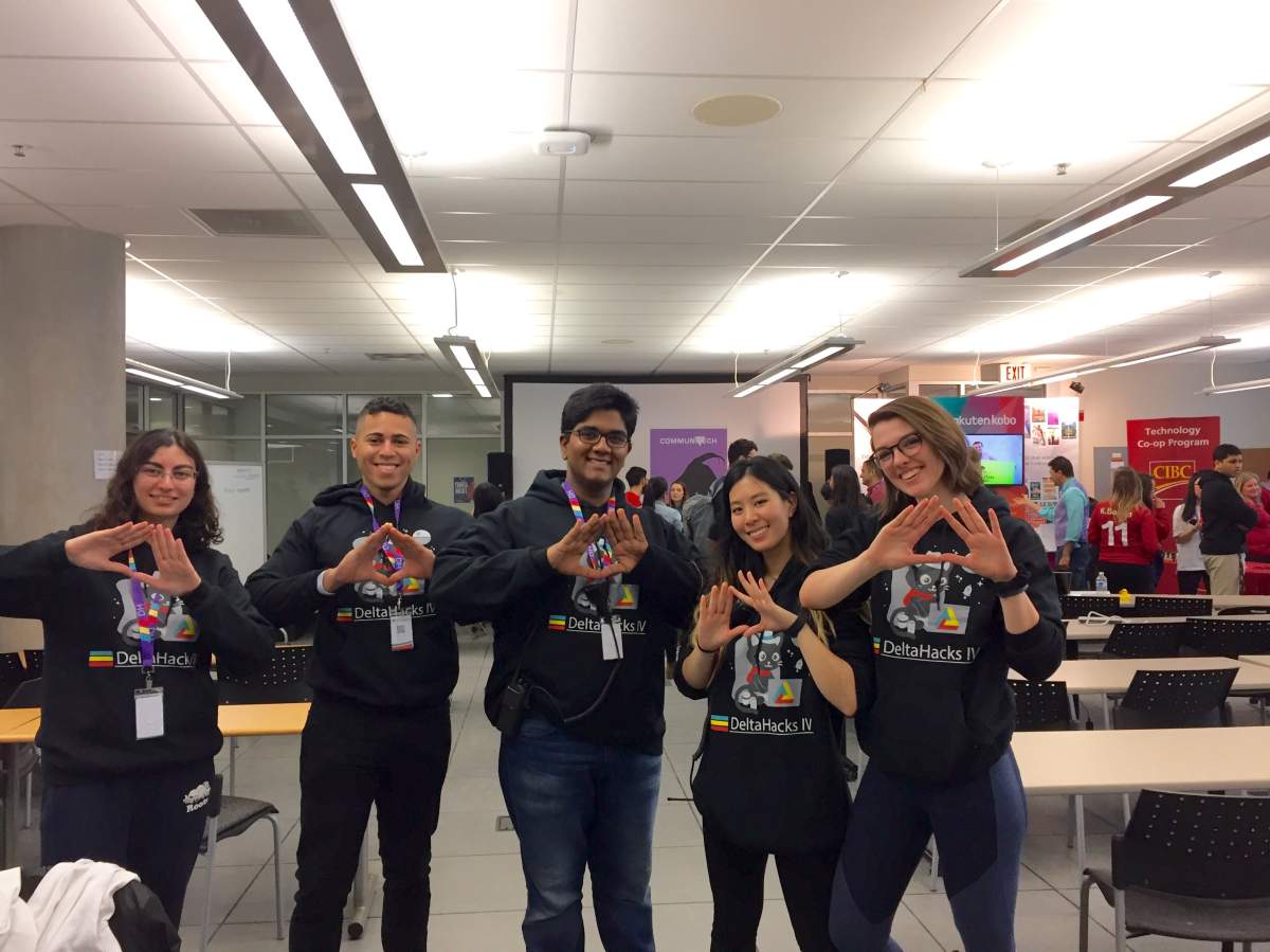 Stephanie Koehl (right) and her fellow students make the "Delta" hand symbol at McMaster University's fourth annual DeltaHacks hackathon.