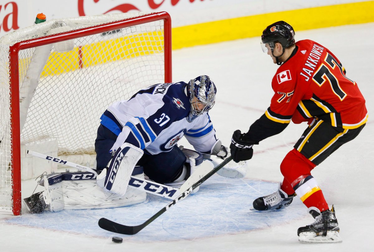 Winnipeg Jets goalie Connor Hellebuyck (37) makes a save on Calgary Flames' Mark Jankowski during the shootout in their NHL hockey game in Calgary, Saturday, Jan. 20, 2018.THE CANADIAN PRESS/Todd Korol.