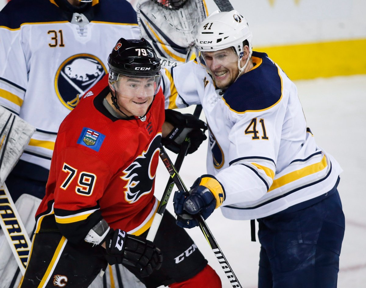 Buffalo Sabres' Justin Falk, right, pushes Calgary Flames' Micheal Ferland away from the front of the net during first period NHL hockey action in Calgary, Monday, Jan. 22, 2018.THE CANADIAN PRESS/Jeff McIntosh.