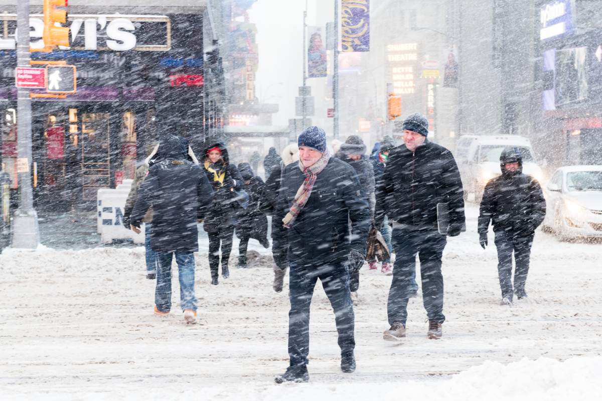 TIMES SQUARE, NEW YORK, NY, UNITED STATES - 2018/01/04: People seen crossing the road during snow storm in Times Square. New York city is under heavy snow storm as a giant winter "bomb cyclone" walloped the East Coast of United States with freezing cold air and heavy snow.
