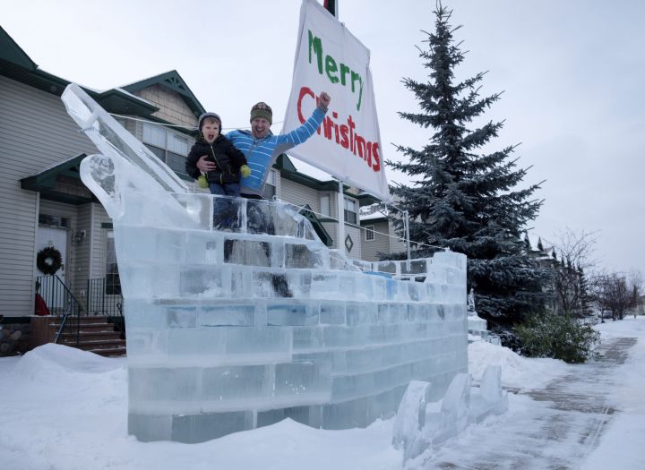 Donnie White and his four year-old son Mateo pose with the ice ship Donnie built on their front yard using frozen blocks of ice from a nearby pond in Red Deer, Alta., Wednesday, Jan. 10, 2018. 