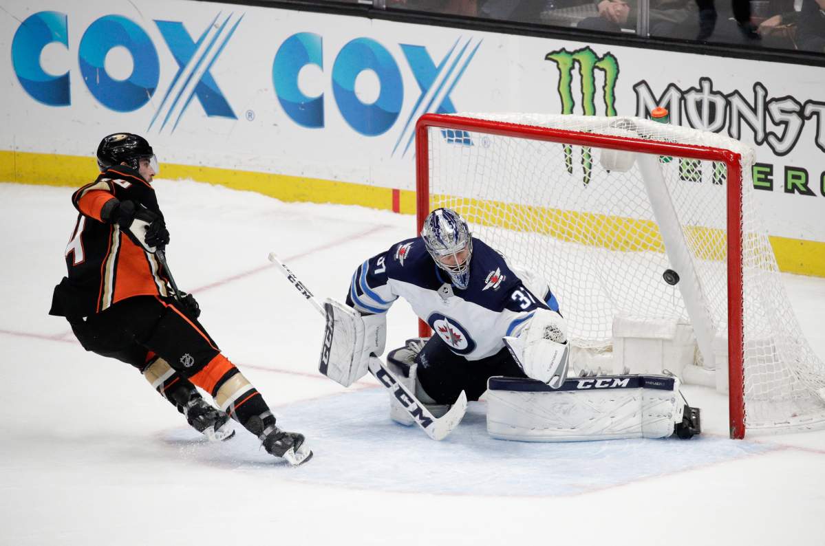 Anaheim Ducks' Adam Henrique, left, scores against Winnipeg Jets goaltender Connor Hellebuyck during the shootout in an NHL hockey game Thursday, Jan. 25, 2018, in Anaheim, Calif. The Ducks won 4-3. (AP Photo/Jae C. Hong).