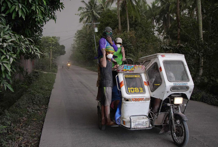 Residents, wearing masks, go on their daily business as Mayon volcano’s eruption plunge some townships in darkness Monday, Jan. 22, 2018 in Legazpi city, Albay province, Philippines.