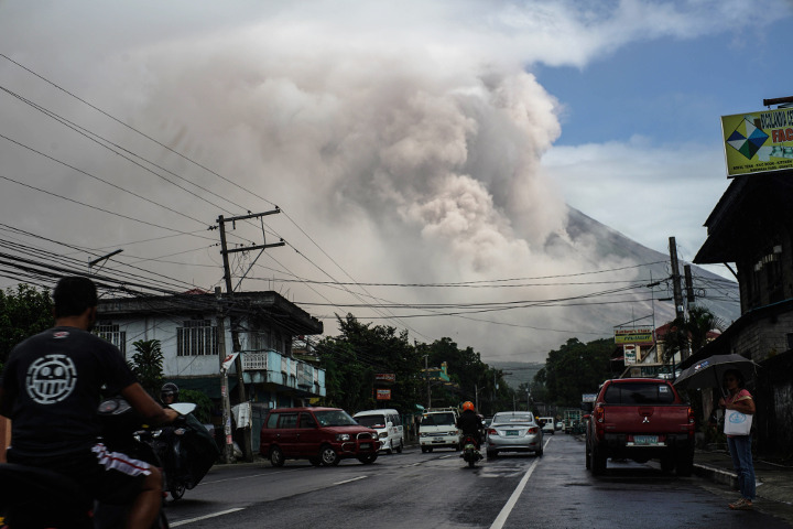 Motorists travel on a highway as Mount Mayon shot up a giant mushroom-shaped cloud as it continues to erupt near Camalig town in Albay province on January 22, 2018.