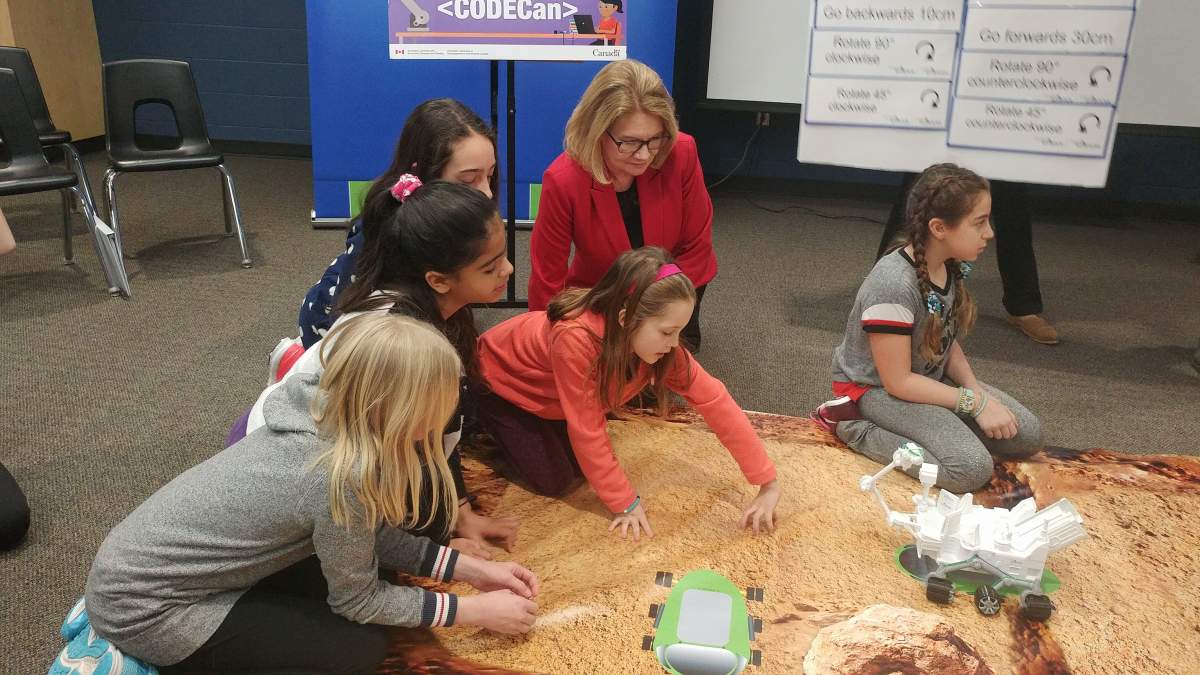 MP for London West, Kate Young helps Grade 5 & 6 students at 
West Oaks French Immersion Public School in London, Ont., program a model rover on a Mars map.