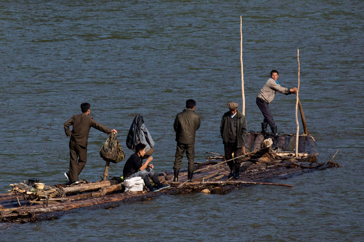 In this Aug. 30, 2017 photo, North Korean men ride a makeshift raft made of fastened logs down the Yalu river that divides North Korea from the Chinese border town of Linjiang in northeastern China's Jilin province. 