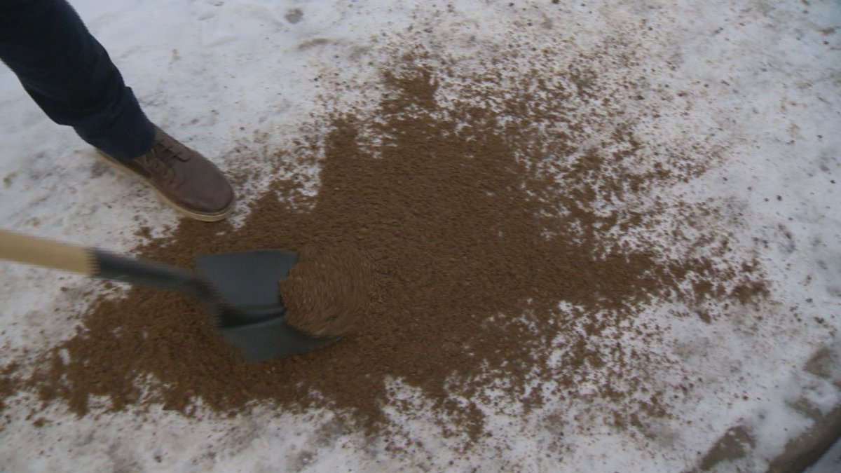 Sand is shoveled onto an icy sidewalk. 
