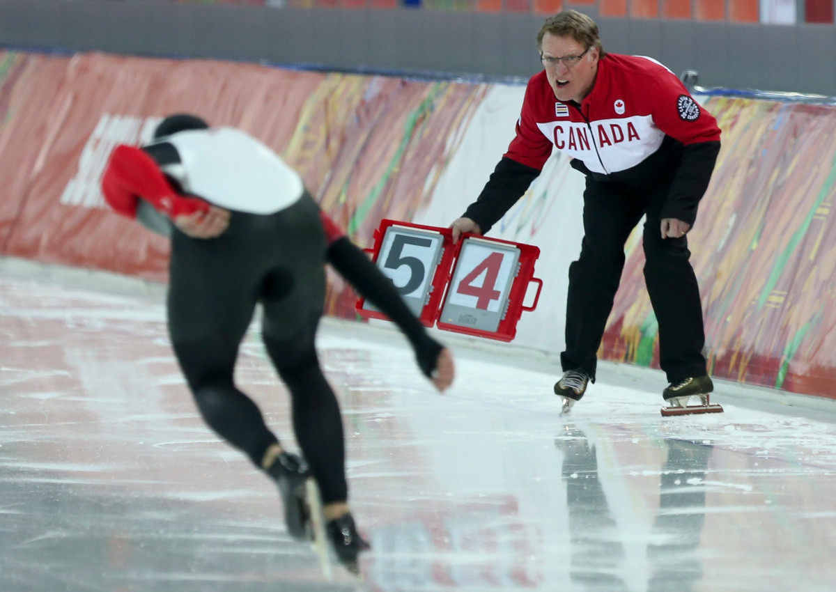 A skater gets instruction from his coach Michael Crowe as he skates in long track speed skating at the Sochi Winter Olympics in Sochi, Russia, Saturday, Feb. 15, 2014.