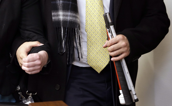 In this Wednesday, Feb. 20, 2013 photo, Rep. Cyrus Habib, D-Kirkland, holds his folded cane as he takes the arm of a legislative assistant as they leave a committee hearing in Olympia, Wash.