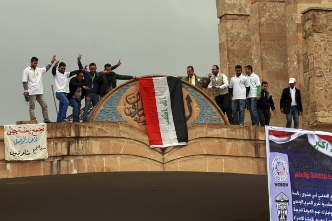 Mosul University students and activists place a national flag at the entrance of their university as they celebrate the liberation from Islamic State militants, on the eastern side of Mosul, Iraq, Sunday, Jan. 22, 2017. 

