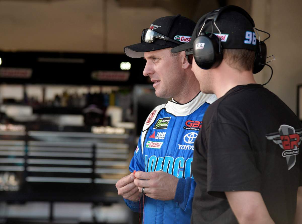 DJ Kennington, left, watches crew members work on his car during practice for Sunday's Daytona 500 at Daytona International Speedway in Daytona Beach, Fla., Friday, Feb. 24, 2017. (AP Photo/Phelan M. Ebenhack).