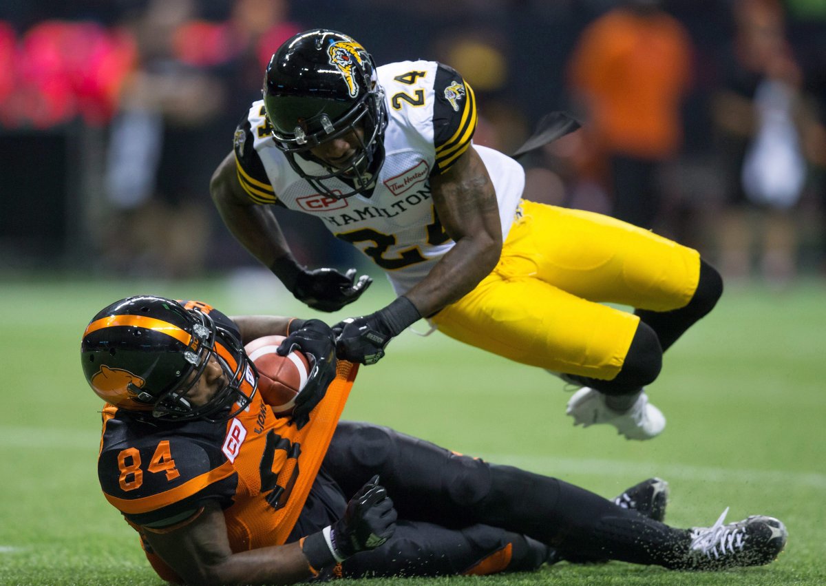 Hamilton Tiger-Cats' Demond Washington, top, falls on B.C. Lions' Emmanuel Arceneaux after Arceneaux made a reception during the first half of a CFL football game in Vancouver, B.C., on Friday September 22, 2017. 