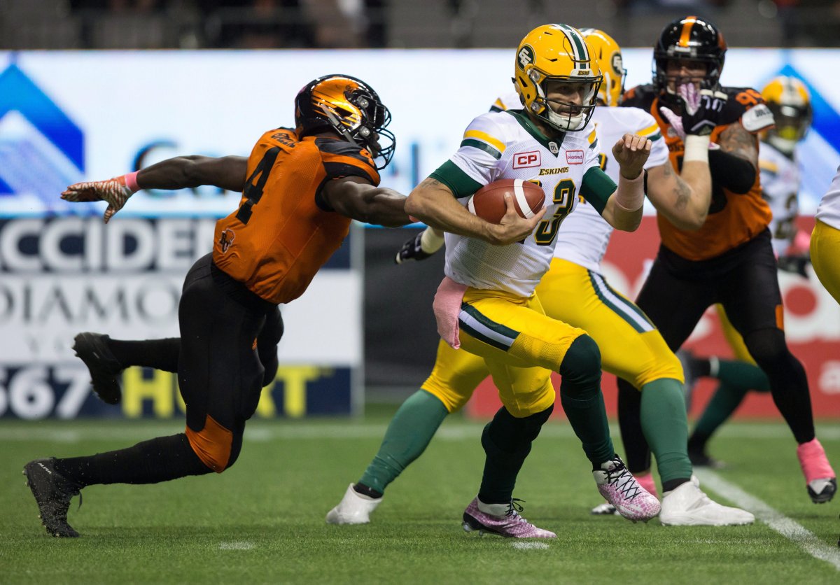 Edmonton Eskimos quarterback Mike Reilly, right, gets away from B.C. Lions' Alex Bazzie during the first half of a CFL football game in Vancouver, B.C., on Saturday October 21, 2017. 