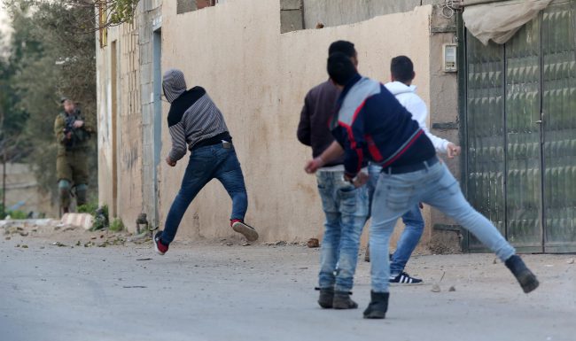 Palestinians throw stones at Israeli troops  during an army operation in the West Bank village of Burqin, near Jenin City, Feb. 3, 2018.