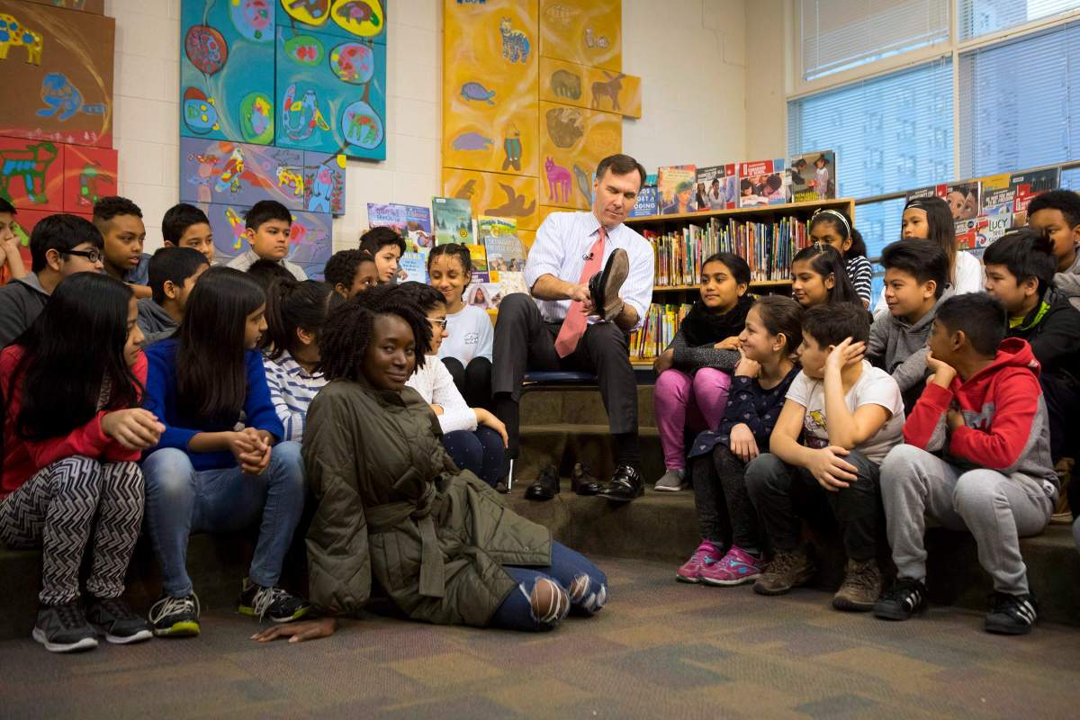 Federal Finance Minister Bill Morneau is joined by students from Toronto's Rose Avenue Junior Public School and his adopted daughter Grace as he tries on a pair of shoes from Edmonton's Poppy Barley Shoe manufacturer during a pre-budget photo opportunity in Toronto on Friday February 23, 2018. 