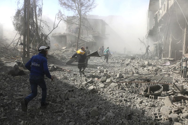 In this photo released on Tuesday Feb. 20, 2018 which provided by the Syrian Civil Defense group known as the White Helmets, shows members of the Syrian Civil Defense run to help survivors from a street that attacked by airstrikes and shelling of the Syrian government forces, in Ghouta, suburb of Damascus, Syria. A Syrian monitoring group and paramedics say government shelling and airstrikes on rebel-held suburbs of the capital, Damascus, killed at least 98 people on Monday. (Syrian Civil Defense White Helmets via AP)

.
